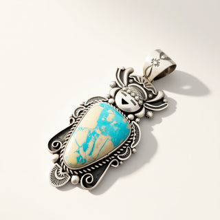 A Southwestern-style silver pendant featuring a turquoise and cream marbled cabochon stone, photographed on a clean off-white background with a soft shadow.