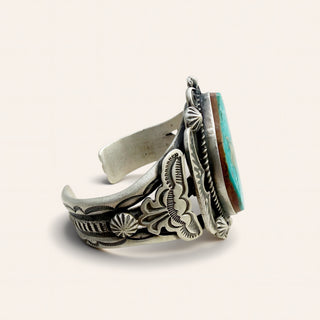 Silver ring with intricate designs and a turquoise stone on a light background