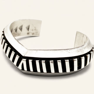 Silver bracelet with black and white striped design on a white background