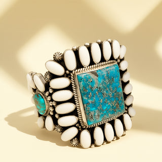 Cuff with turquoise stones and white beads on a beige background