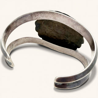 Silver bracelet with a dark stone on a white background