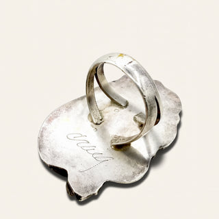 Silver ring on a textured silver base with 'Jewelry' engraving on a light gray background