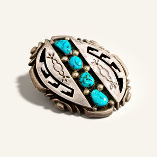Silver belt buckle with blue stones on a beige background