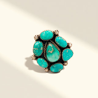 Turquoise ring with silver accents on a beige background