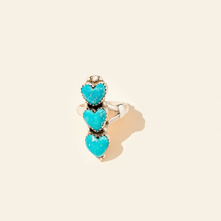 Ring with turquoise heart-shaped stones on a beige background