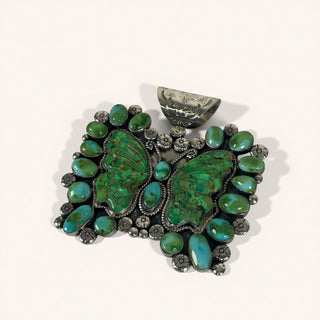 Turquoise butterfly-shaped pendant on a white background