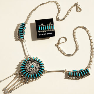 Silver and turquoise necklace with matching earrings on a beige background